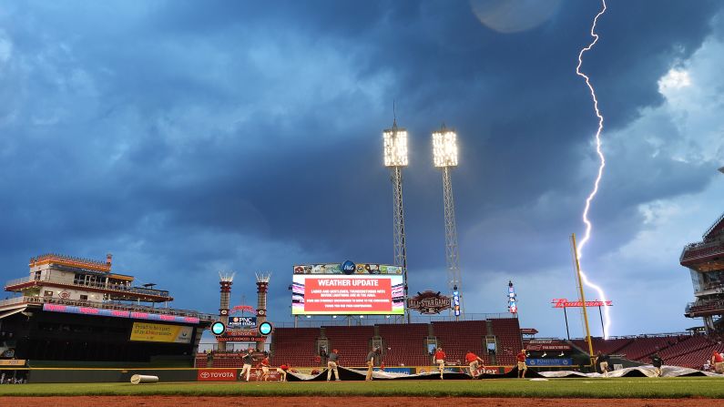 Lightning strikes in the distance as a grounds crew pulls a tarp over the field at Cincinnati's Great American Ball Park on Saturday, September 5.