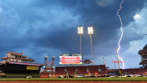 Lightning strikes in the distance as a grounds crew pulls a tarp over the field at Cincinnati's Great American Ball Park on Saturday, September 5.