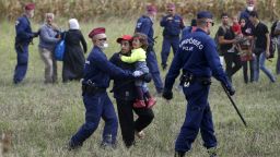 Hungarian police officers stop refugees from leaving a cordoned off area in Roszke, Hungary, on September 8.
