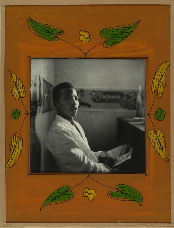 Malick Sidibe is famous for capturing the transition between colonial and post-colonial Mali. In this rare self-portrait Sidibe appears animated, even surprised, within his own composition.<br /><br />Self-Portrait, 1956<br />Malick Sidibe (Malian, b. 1936)<br />Gelatin silver print in original frame of reverse-painted glass, tape, cardboard, string