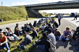 A group of migrants sit down on the highway in southern Denmark.
