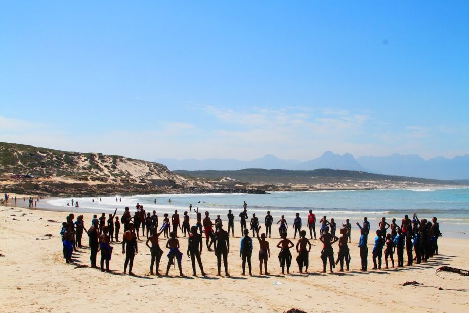 Surf students and coaches warm up on the beach with a safe circle. W4C says safe circles encourage sharing and create a respectful culture. 