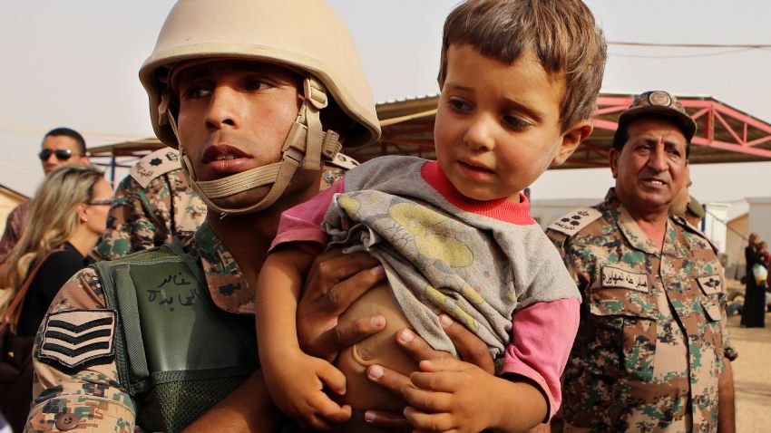 In this Thursday, Sept. 10, 2015 photo, a Jordanian soldier carries a Syrian child arriving in Jordanian territory in the Roqban reception point near the northeastern Jordanian border with Syria, and Iraq, near the town of Ruwaished, 240 km (149 miles) east of Amman. The commander of Jordan's Border Guard told The Associated Press that 199 refugees crossed from Syria into Jordan on Thursday. (AP Photo/Raad Adayleh)