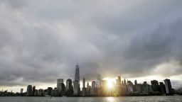 The sun rises, as One World Trade Center, center left, stands on the 14th anniversary of the Sept. 11, 2001 terrorist attacks, Friday, Sept. 11, 2015, in Jersey City, N.J. Victims' relatives began marking the 14th anniversary of Sept. 11 in a subdued gathering Friday at ground zero, with a moment of silence and somber reading of names. (AP Photo/Mel Evans)