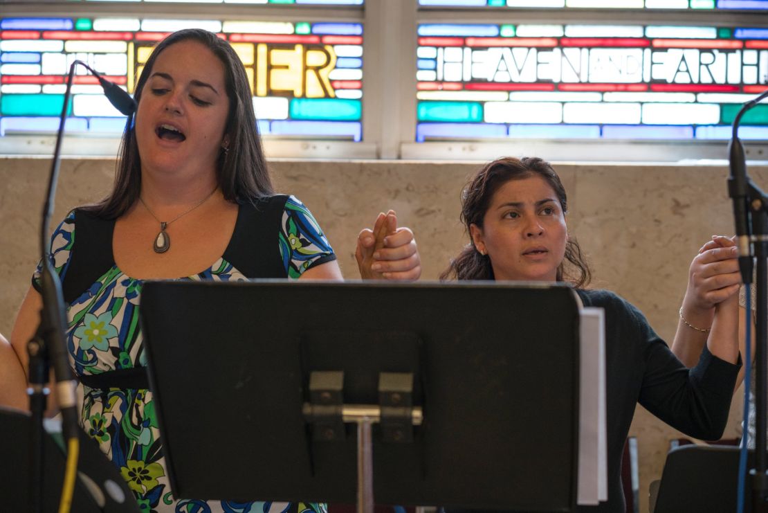 Danielle Quaglia (left), a 30-year-old who's attended Saint Charles Borromeo her whole life, sings the Lord's Prayer with a Spanish choir group she's just joined. "I love to sing...to share my talent that God gave me, hopefully to inspire others and make others feel welcome," she says.