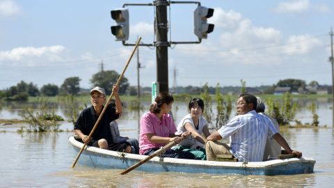 People paddle a boat on a flooded road in Joso, Japan, on Friday, September 11. The sun came out a day after floods washed away houses and forced people to rooftops waiting for rescue.