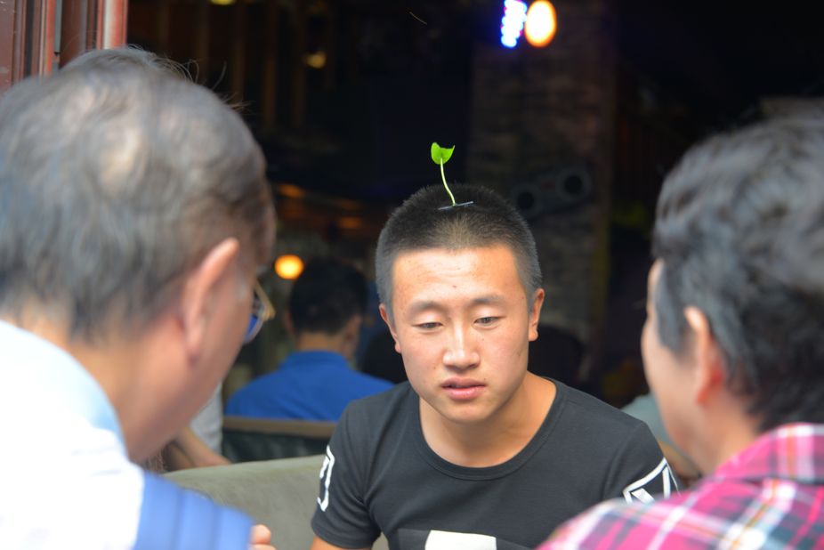 A bartender wears a sprout hair clip in Beijing's Nanluoguxiang, trying to draw in costumers on September 11, 2015.