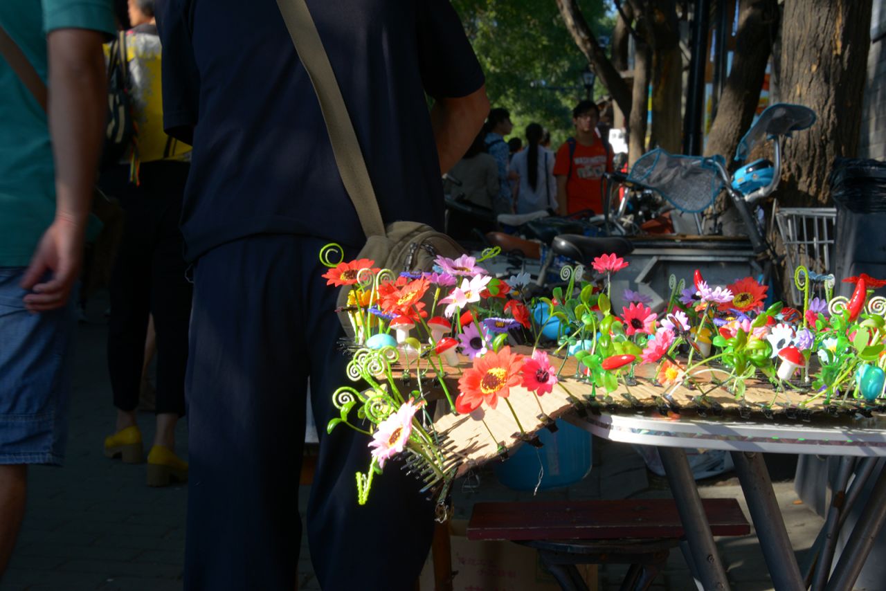 Tourists pass by a tray of hair clips in a variety of forms in Nanluoguxiang, Beijing.