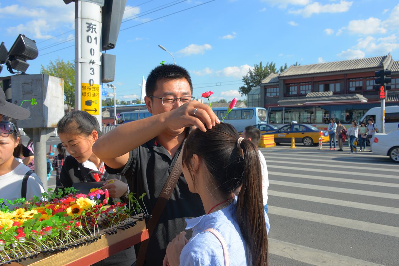 In Nanluoguxiang, an ancient stone lane in Beijing, excited tourists try on sprout and flower hair clips on September 11, 2015.
