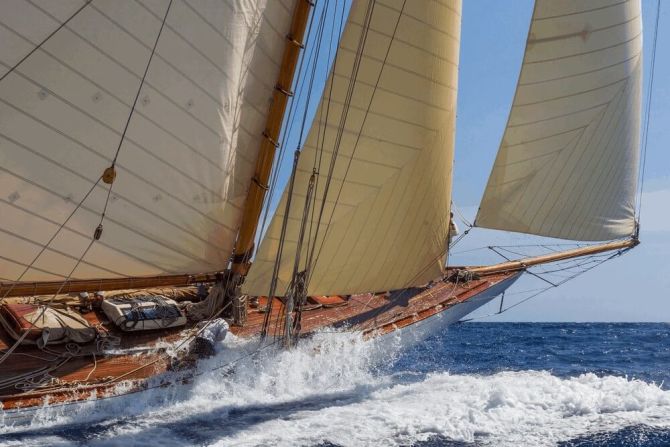 A sailor clings onto the deck as this vessel crashes through the waves, with water pouring overboard.