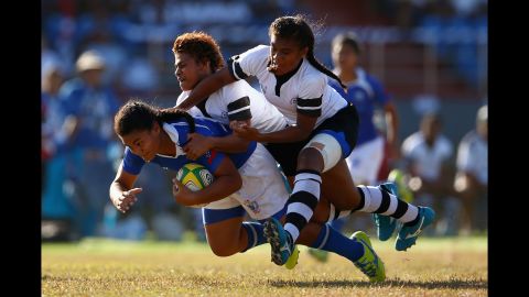 Samoa's Teuila Aukusitino is tackled by two Fiji players during a rugby sevens match at the Commonwealth Youth Games on Wednesday, September 9.