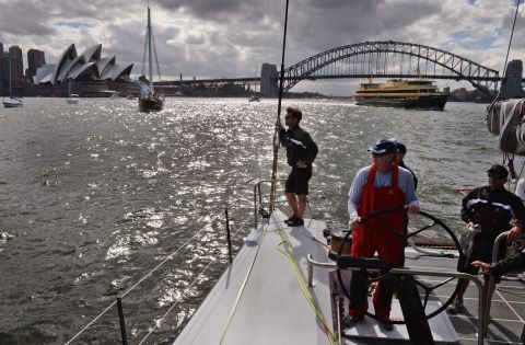 Ken Read, one of sailings most decorated yachtsman, stands at the helm of the French-designed, American-owned yacht Comanche as it sails past the Sydney Opera House and Harbor Bridge in December 2014. The boat is like nothing that has been built before and was made to push the limits of sailing. 