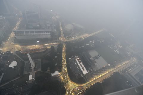 Floodlights pierce the atmosphere to reveal the layout of the race circuit. The haze is caused by farmers in neighboring Indonesia burning forests to clear land, with air quality dropping to unhealthy levels. Paper and palm oil firms are also criticized for the practice. Swathes of Indonesia, Singapore and Malaysia suffer from the resulting air quality problems.