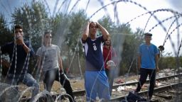Migrants demonstrate with police officers through the razor wire fence from the Serbian side of the Serbian-Hungarian border at the closed rail track crossing point on September 15, 2015 in Roszke, Hungary.