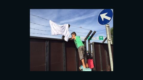 Migrant children in Serbia peer across the border to Hungary.