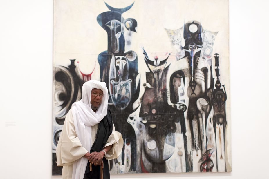 Sudanese artist Ibrahim El-Salahi poses for a photograph in front of his painting entitled "Reborn Sounds of Childhood Dreams" at the Tate Modern in London.
