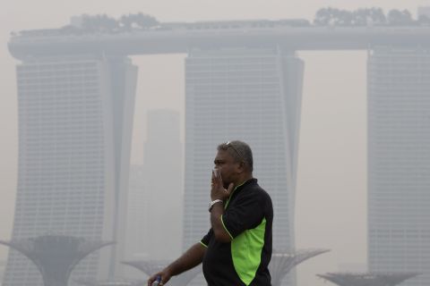 A man covers his nose near Singapore's iconic Marina Bay Sands hotel on September 10, 2015.