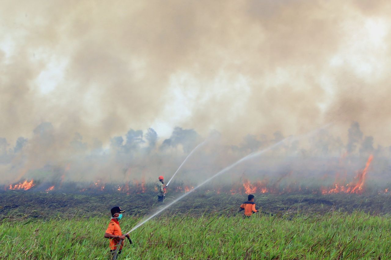 Firemen spray water to contain smoke-belching fires in Ogan Ilir, South Sumatra, Indonesia on September 5, 2015.