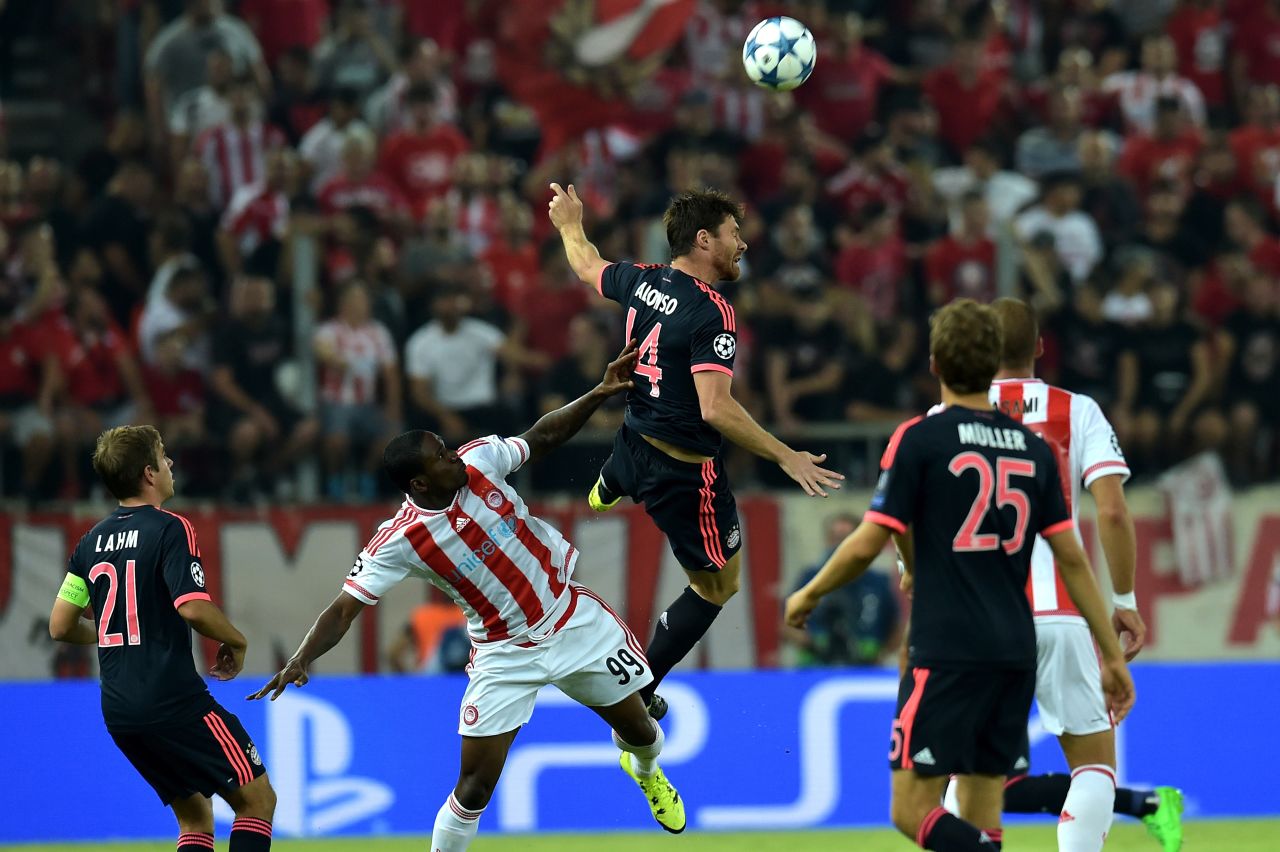 Bayern Munich's Xabi Alonso battles for a high ball with Olympiakos forward Ideye Brown in the Group F game in Greece. Bundesliga champions Bayern were made to work hard before breaking through.
