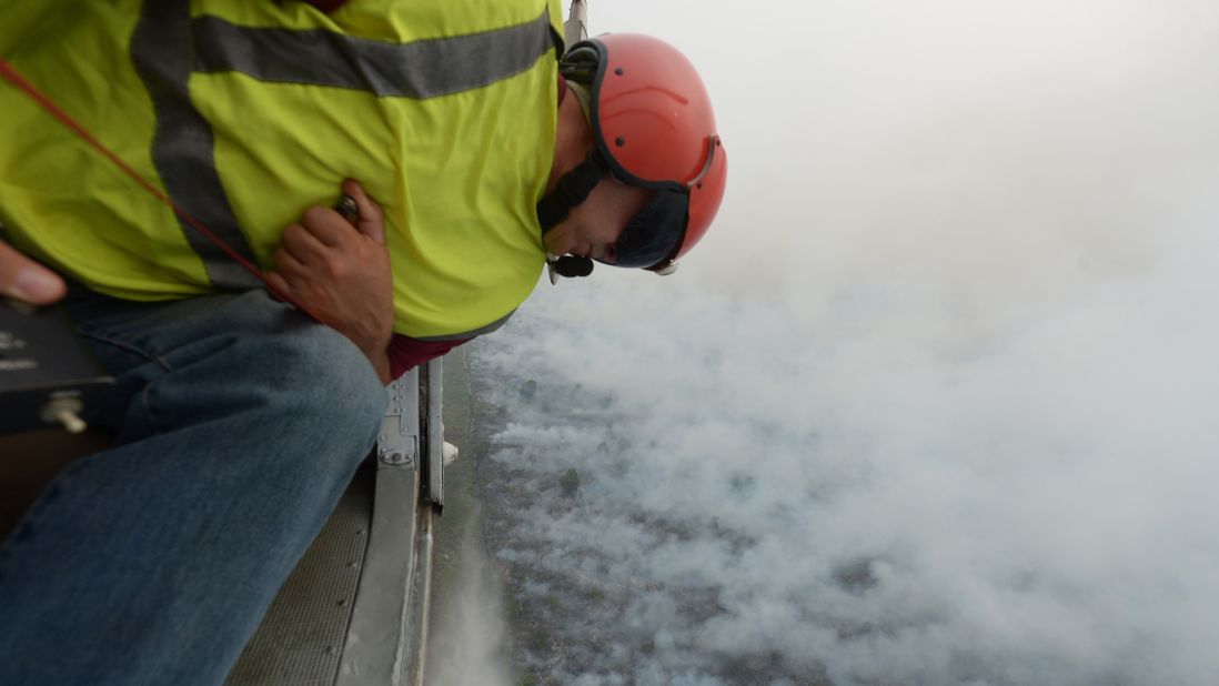 A crew member of a helicopter operated by Indonesia's Disaster Mitigation Agency checks a water-bombing operation in Pelalawan, Riau, Indonesia, on September 17, 2015.