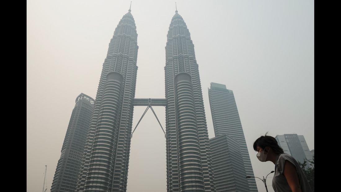 A woman wears a mask as haze shrouds the Petronas Twin Towers in Kuala Lumpur, Malaysia, on Friday, September 11.