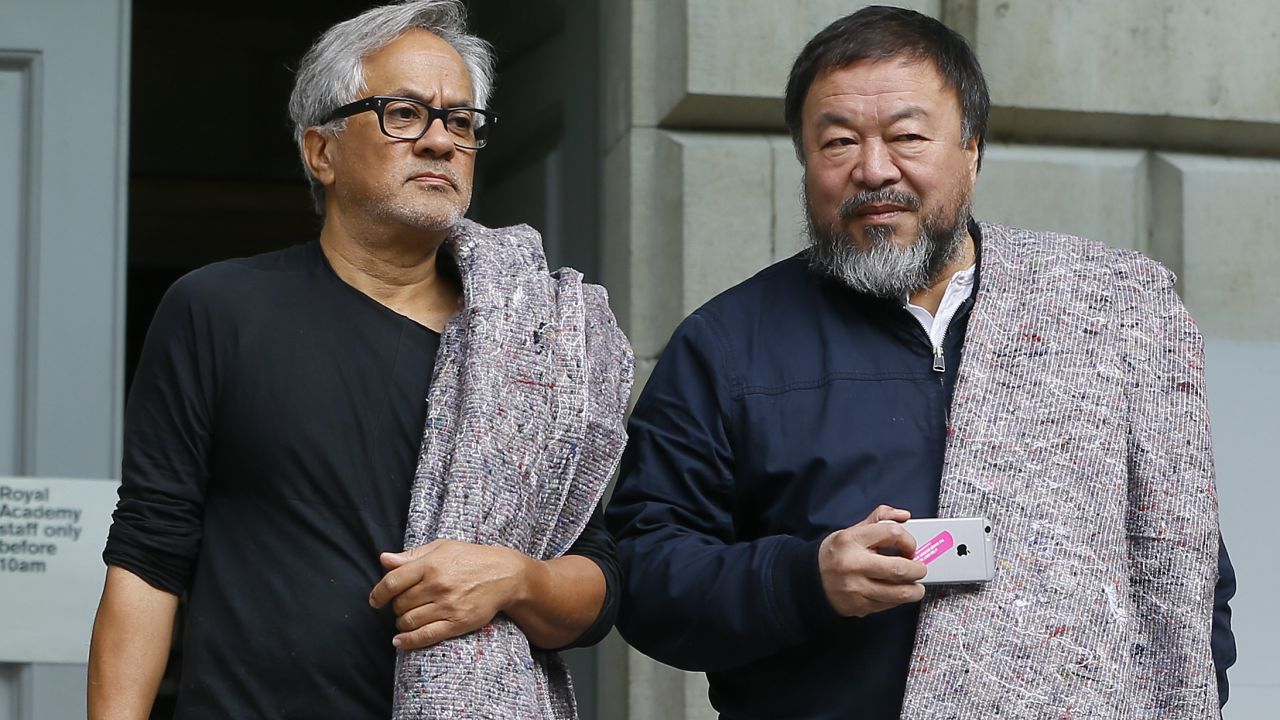 Artists Anish Kapoor, left, and Ai Weiwei  carry blankets as they set off from The Royal Academy of Arts to walk across London in support of refugees, Thursday, Sept. 17, 2015. They carried a single blanket as a symbol of the need that faces 60 million refugees in our world today. The artists will repeat this action in cities across the world over the next few months. (AP Photo/Kirsty Wigglesworth)