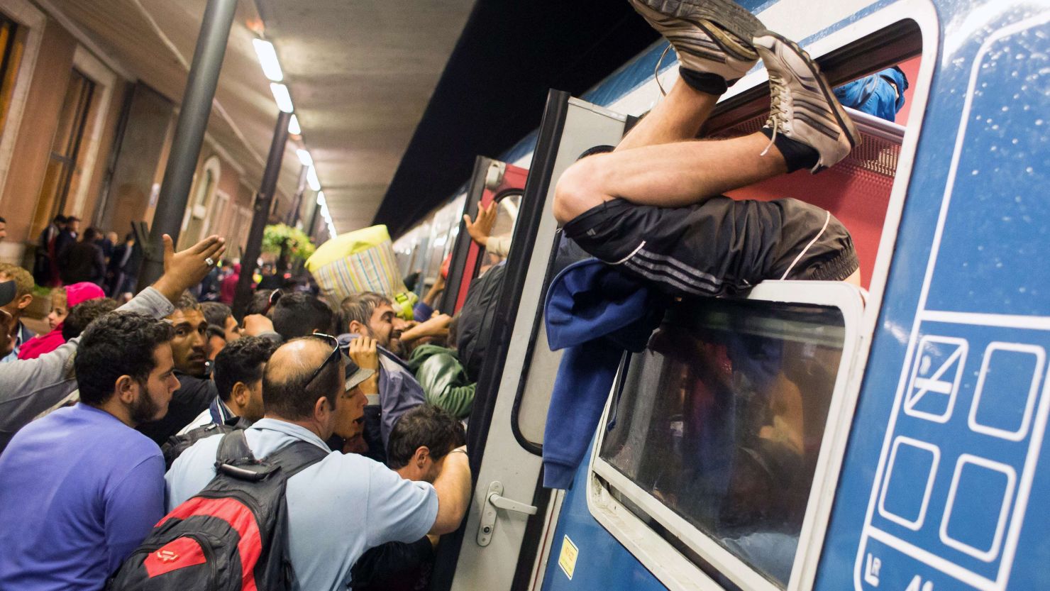 A man climbs through a window as migrants struggle to get on a train in Hungary in September 2015.