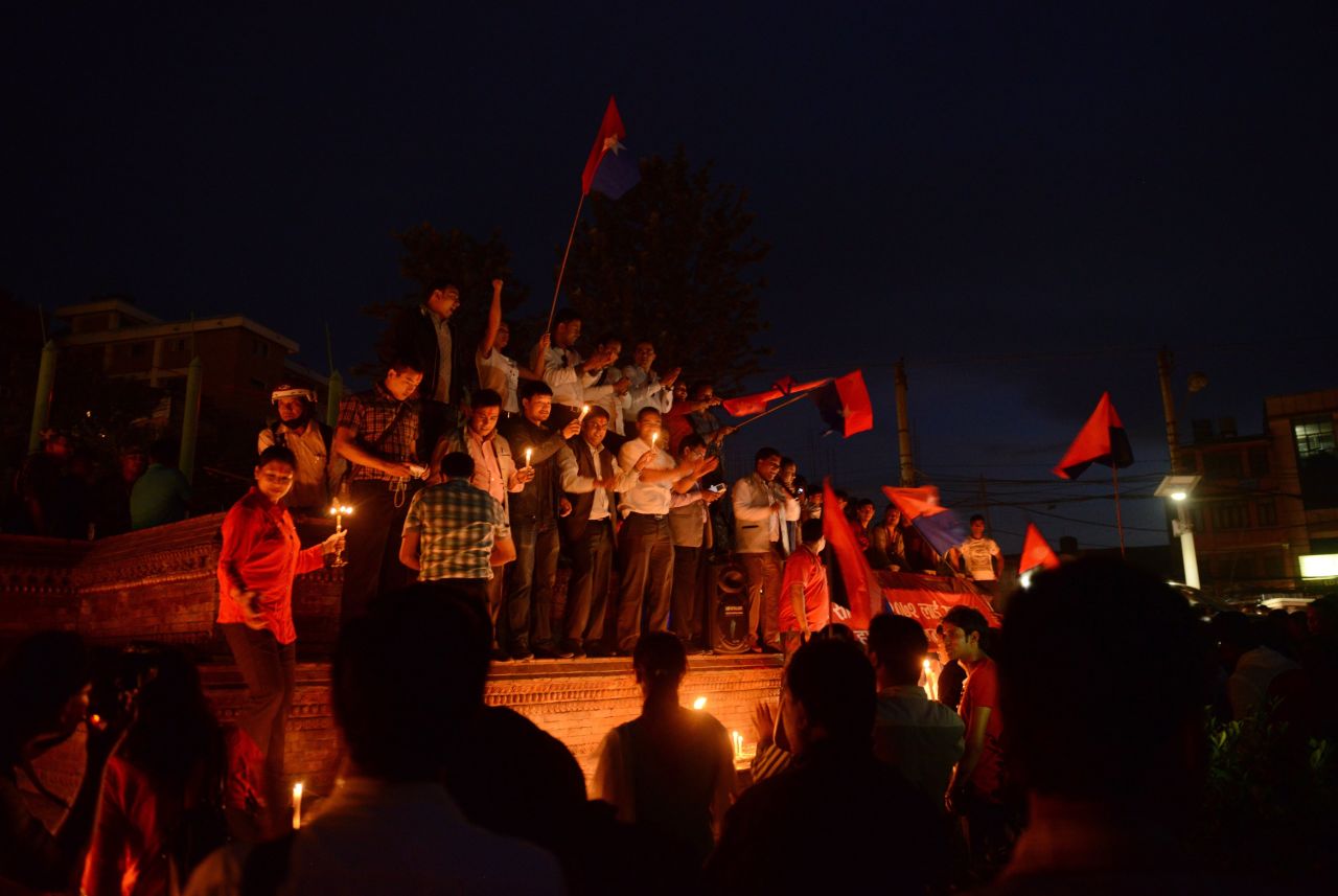 Nepalese youths hold candles and sing as they celebrate Nepal's new national constitution in Kathmandu on September 17, 2015, work on which began in 2008. 
