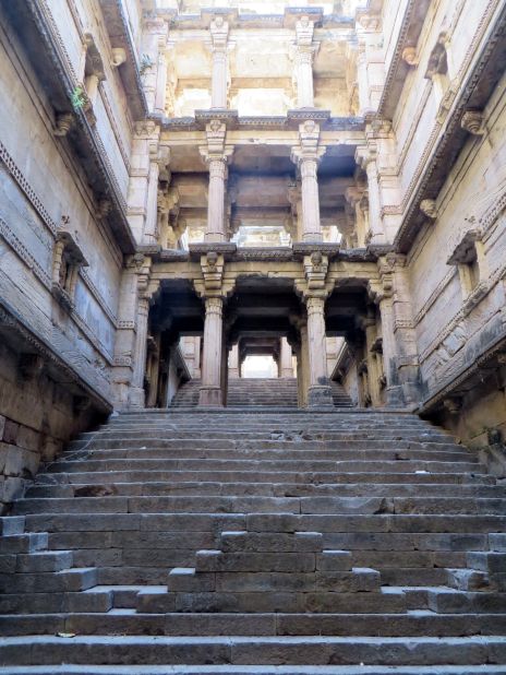 "This impressive, ignored, disintegrating stepwell is in a small village about 15 minutes away from its famous sister, Rudabai vav in Adalaj, and yet no-one ever visits. It was built at the same time, most likely by the same queen, and while less showy and grand it's nevertheless beautiful and elegant, with sculptural niches climbing up the narrow walls. It's "protected" by the local government (even though chunks are falling from it and bonfires have been lit within) but easily accessible through an adjacent temple."