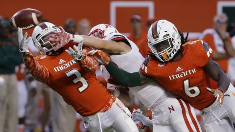 Miami defensive backs Tracy Howard, left, and Jamal Carter break up a pass intended for Nebraska's Brandon Reilly during a college football game in Miami Gardens, Florida, on Saturday, September 19.