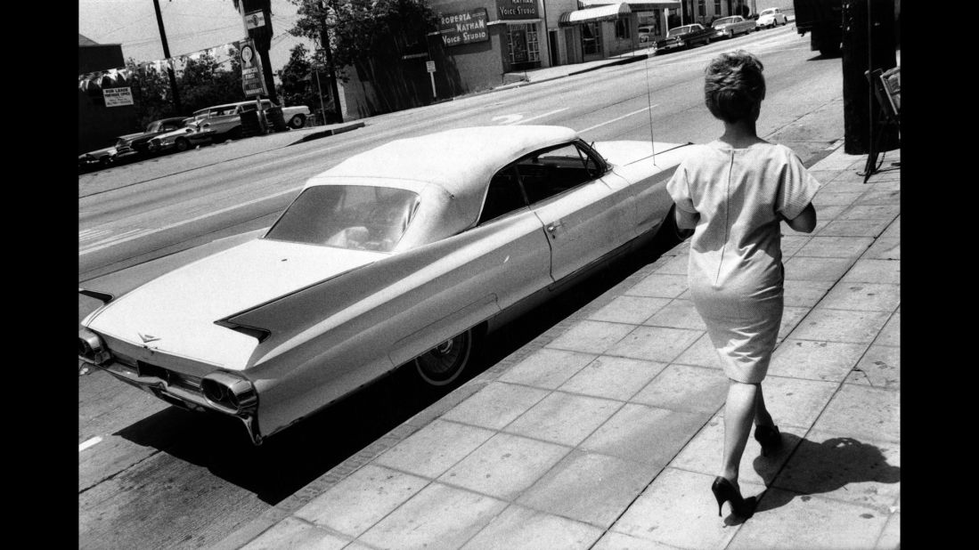 A woman walks by a Cadillac.