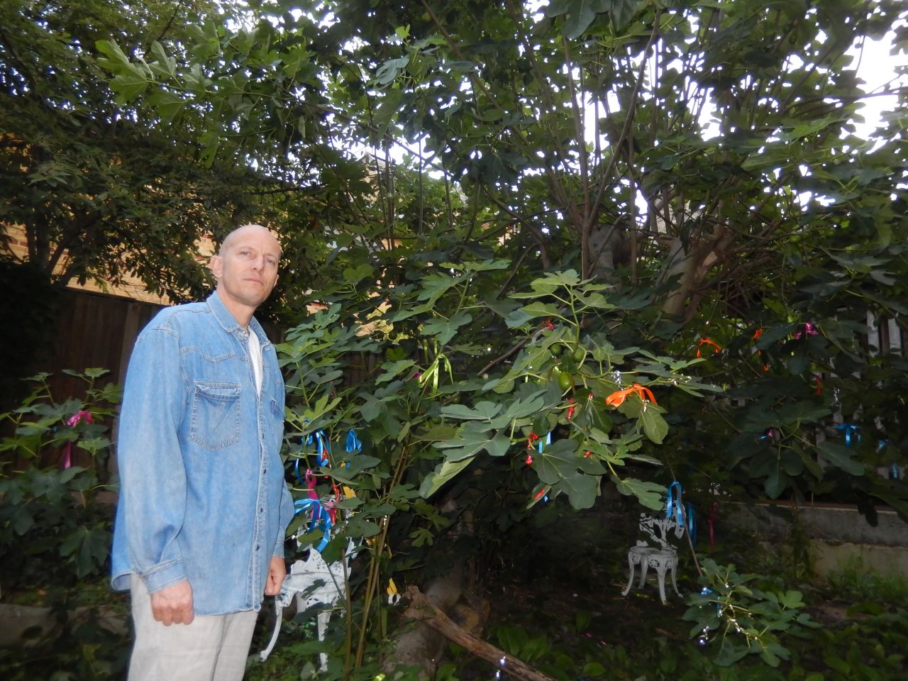 Peter Keserue with the community's fig tree, which he maintains and harvests. 