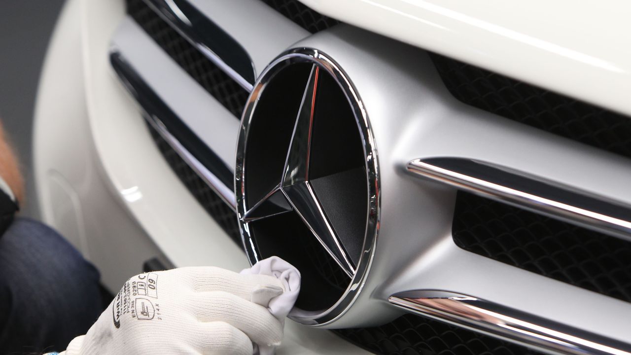 An employee polishes the logo of a car at the Mercedes-Benz factory in Germany.