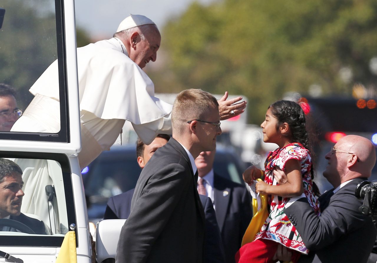 Pope Francis reaches out to bless a child during the parade in Washington.