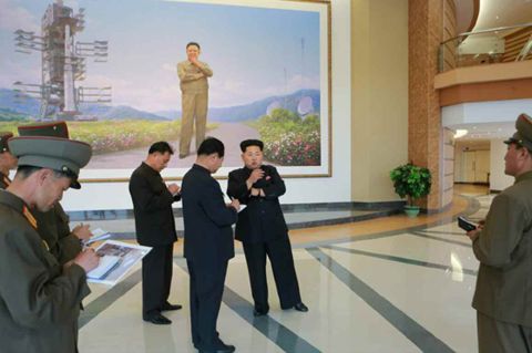 Kim Jong Un is pictured in front of a large painting of his father and former leader, Kim Jong Il, posing next to a satellite inside the satellite control center.
