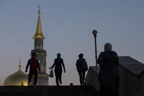 People pass by the mosque as the sun sets. 