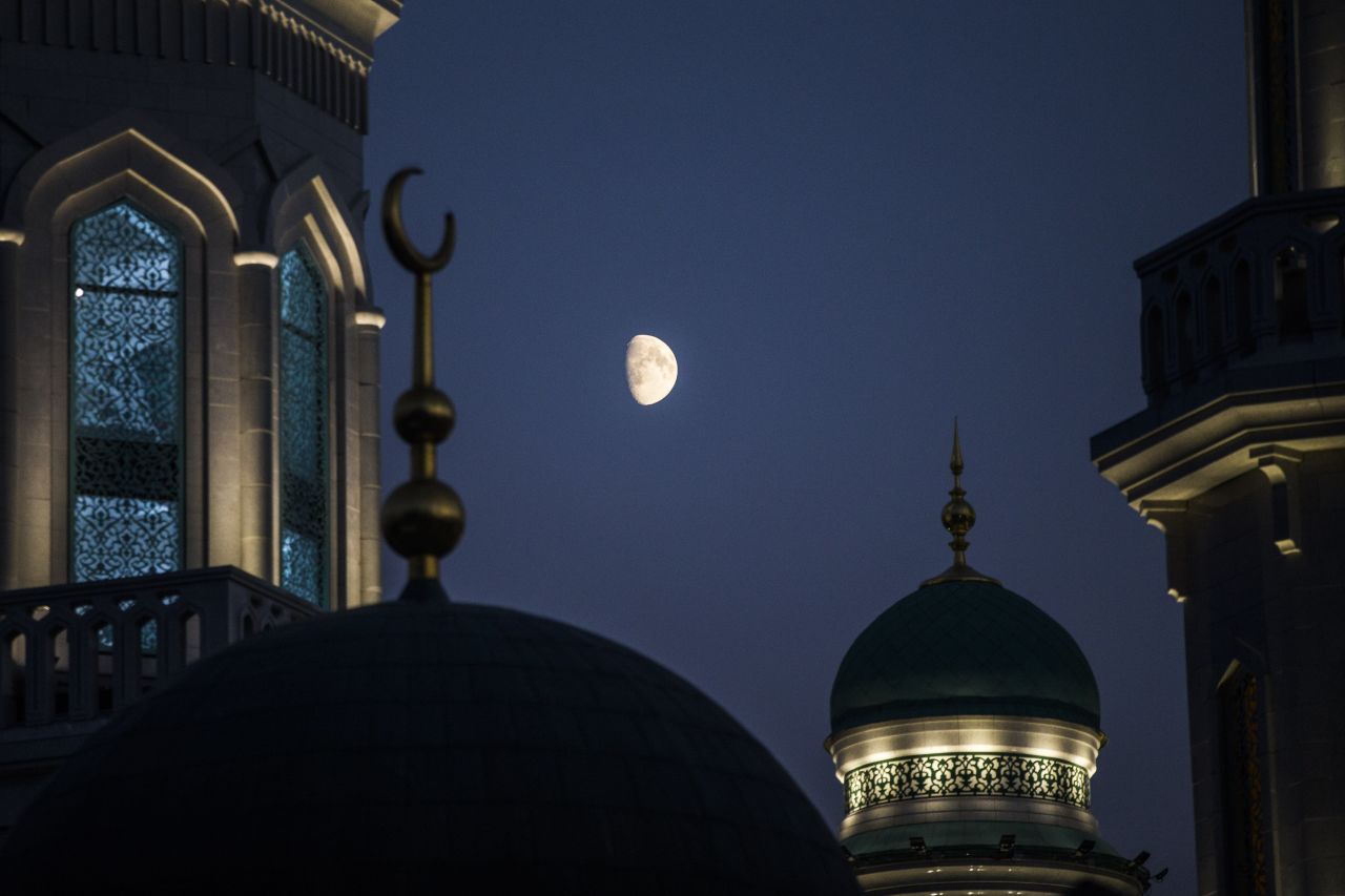 The moon rises over the mosque.