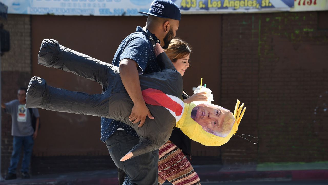 A couple in Los Angeles walks with a pinata of Republican presidential candidate Donald Trump on Wednesday, September 23.