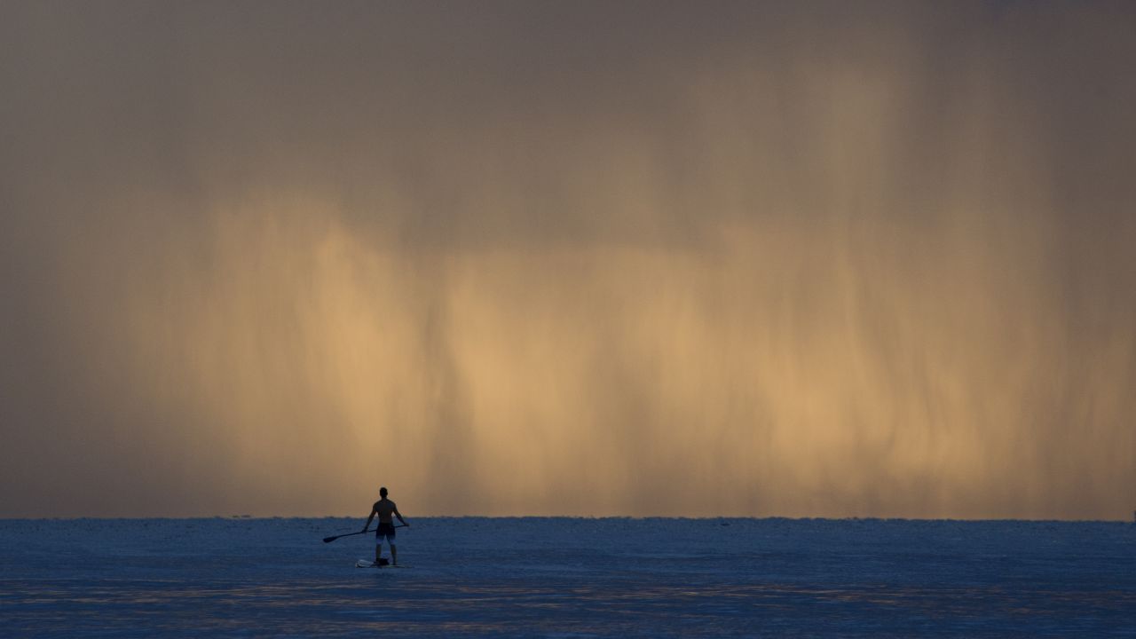 Sheets of rain fall in front of a paddleboarder Tuesday, September 22, in Bal Harbour, Florida.
