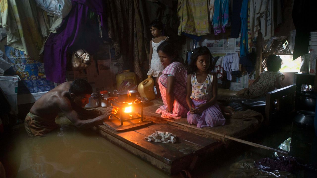 A man lights a stove to make food in his family's flooded house in Gauhati, India, on Wednesday, September 23.