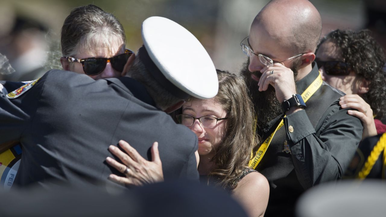 Relatives of late firefighter Robert Taylor embrace one another after being presented with an honorary flag Saturday, September 19, at a fallen firefighter memorial service in Colorado Springs, Colorado.