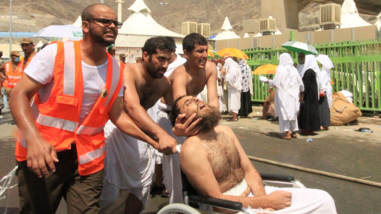 Saudi emergency personnel and Hajj pilgrims push a wounded person in a wheelchair at the site where at least 450 were killed and hundreds wounded in a stampede in Mina, near the holy city of Mecca, at the annual hajj in Saudi Arabia on September 24, 2015. The stampede, the second deadly accident to strike the pilgrims this year, broke out during the symbolic stoning of the devil ritual, the Saudi civil defence service said.