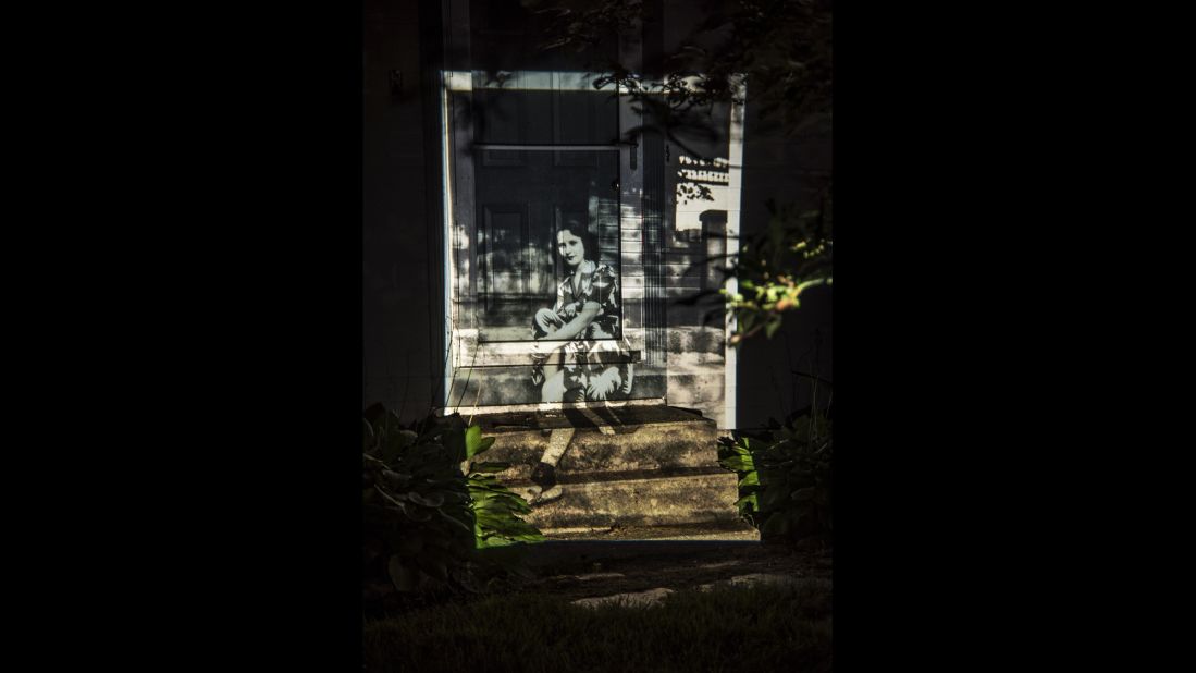 An image of an unknown family member, sitting on a stoop in 1944, is projected onto Cooper's home.