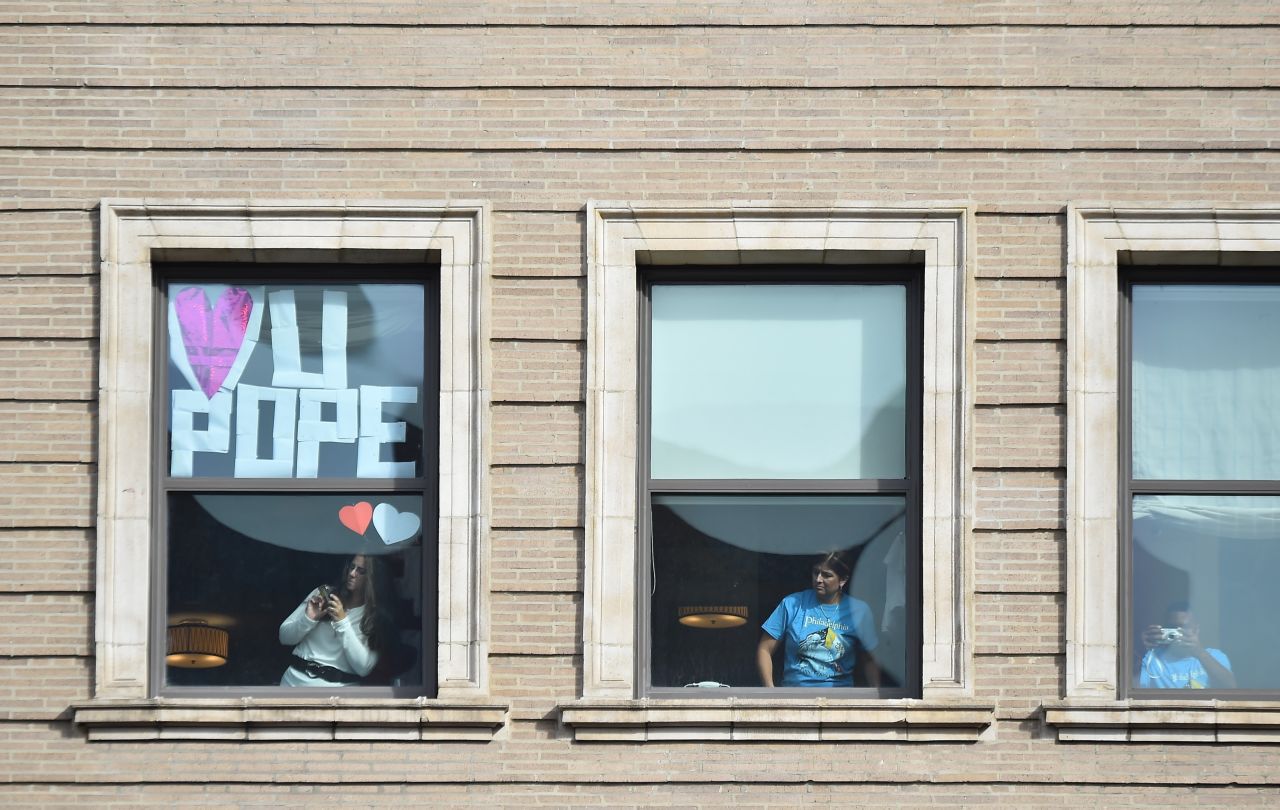 Residents in decorated apartment windows await the arrival of Pope Francis near Independence Mall on September 26.