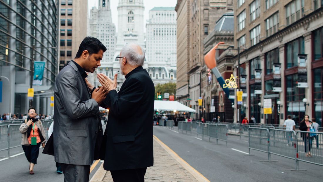 A priest blesses a Catholic man on the way to see Pope Francis speak.