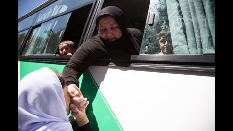 A Yazidi woman kisses the hand of a relative before a bus takes women and children who were captives of ISIS to an airport in the Kurdish region of Iraq. From there, they will fly to Germany, where the German government is resettling up to 1,000 former captives of ISIS, giving them housing and psychological treatment.