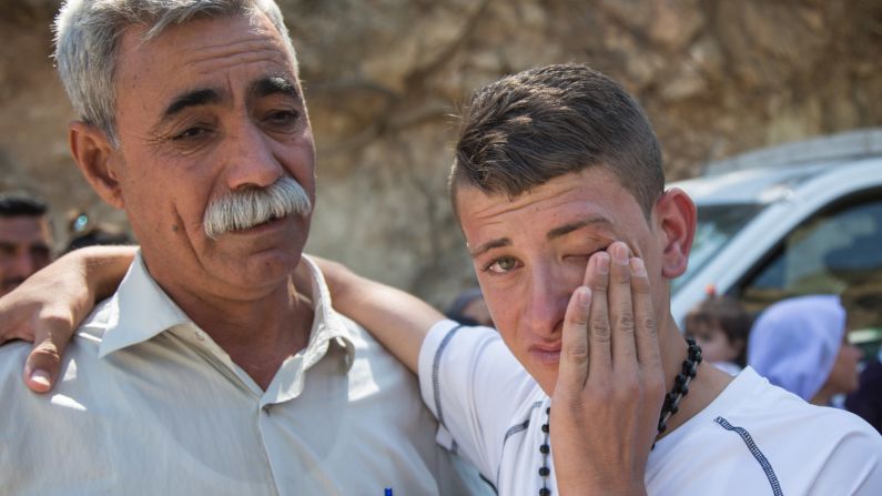 Sabah Mirza Mahmoud, right, cries next to his uncle Jamil Jato as Mahmoud and his sisters prepare to leave for Germany.