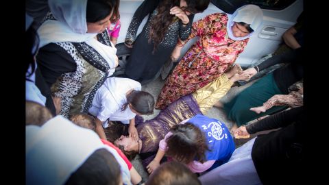 A Yazidi girl faints while saying goodbye to relatives who are going to Germany.