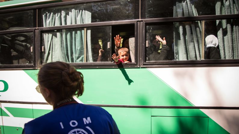 Women and children wave goodbye to relatives before their journey to Germany.