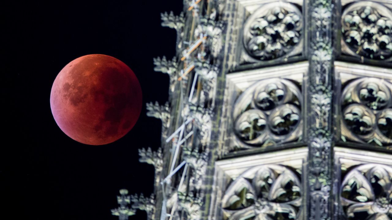 The eclipsed supermoon is seen next to one of the steeples of the Cologne Cathedral in Germany.